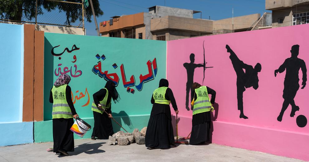 Women clear the grounds of a school for boys in West Mosul