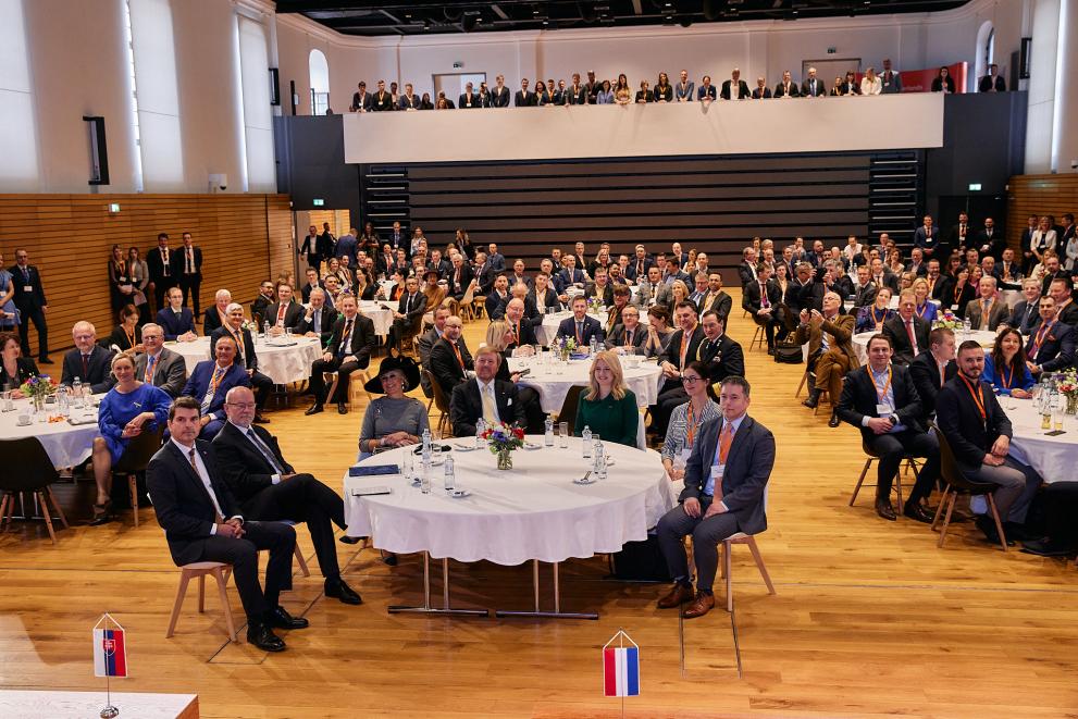 big group seated in a hall with King and Queen